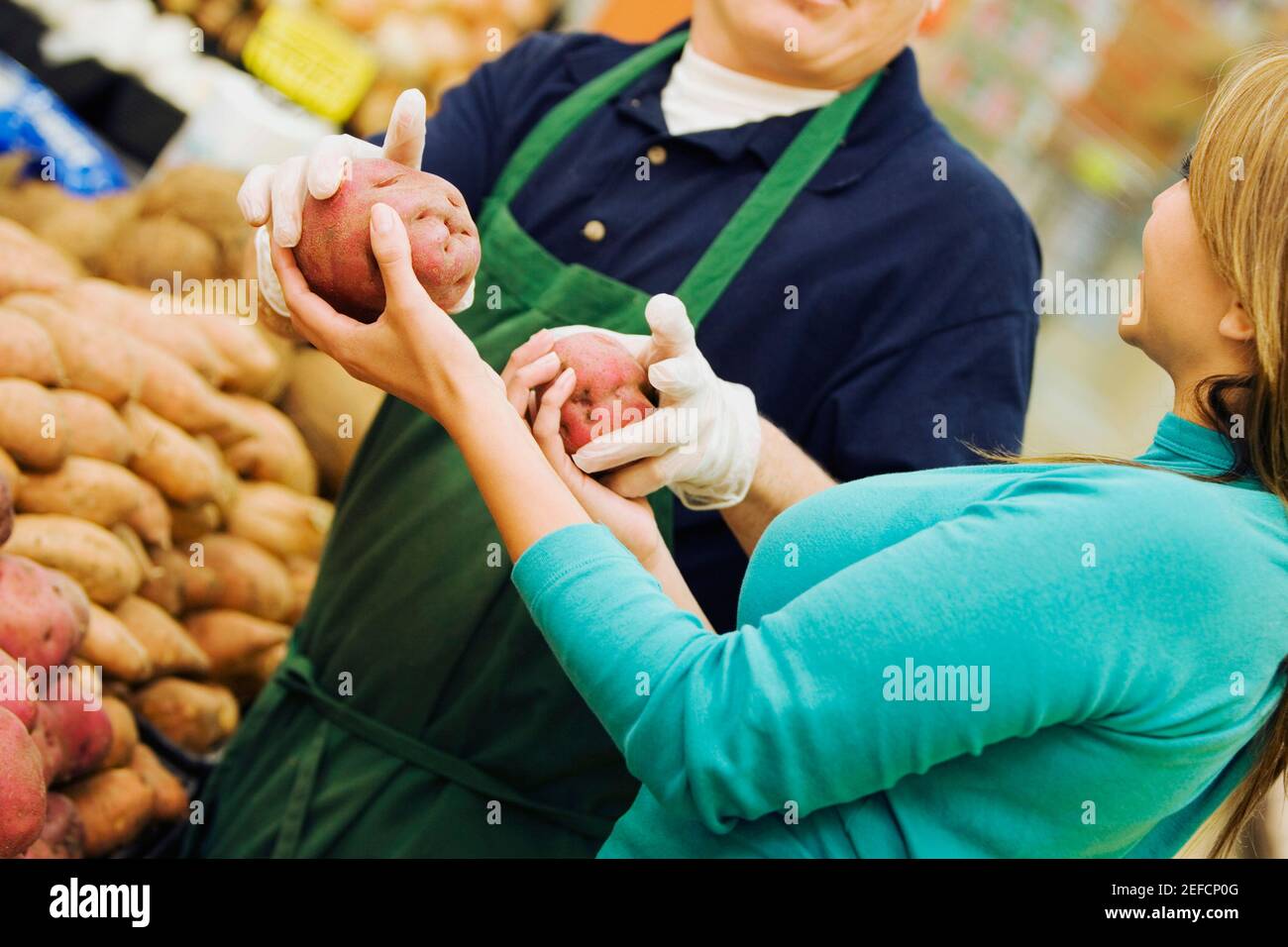 Mid section view of a man giving raw potatoes to a young woman Stock Photo