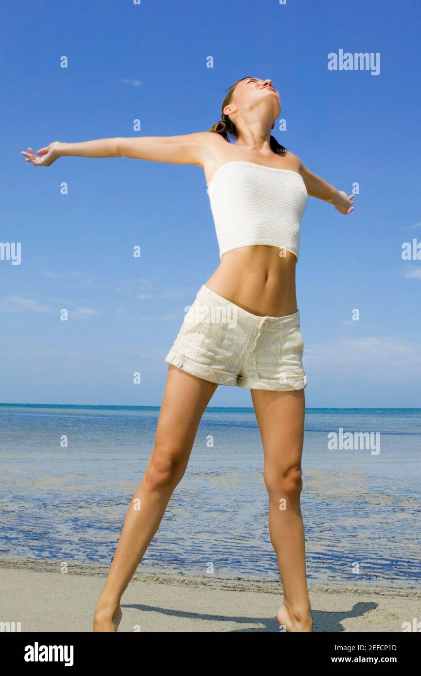 Young woman standing on the beach with her arms outstretched Stock ...