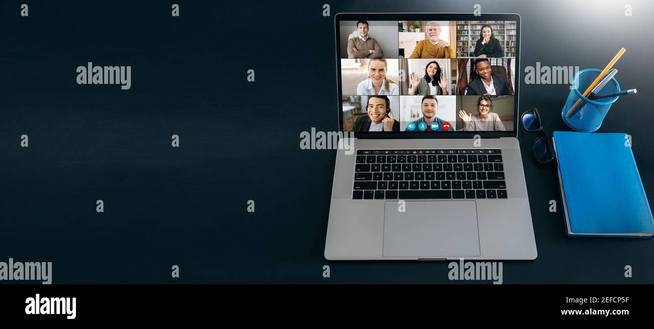 Online business briefing, webinar. Panoramic photo of a laptop screen with webcam shots of multiracial diverse business people communication from home by a video conference. Brainstorm, virtual Stock Photo