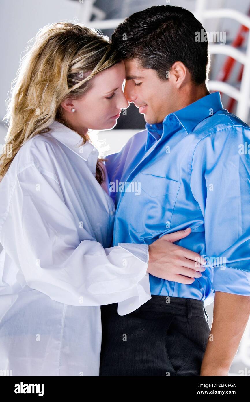 Side profile of a young woman and a mid adult man embracing each other ...