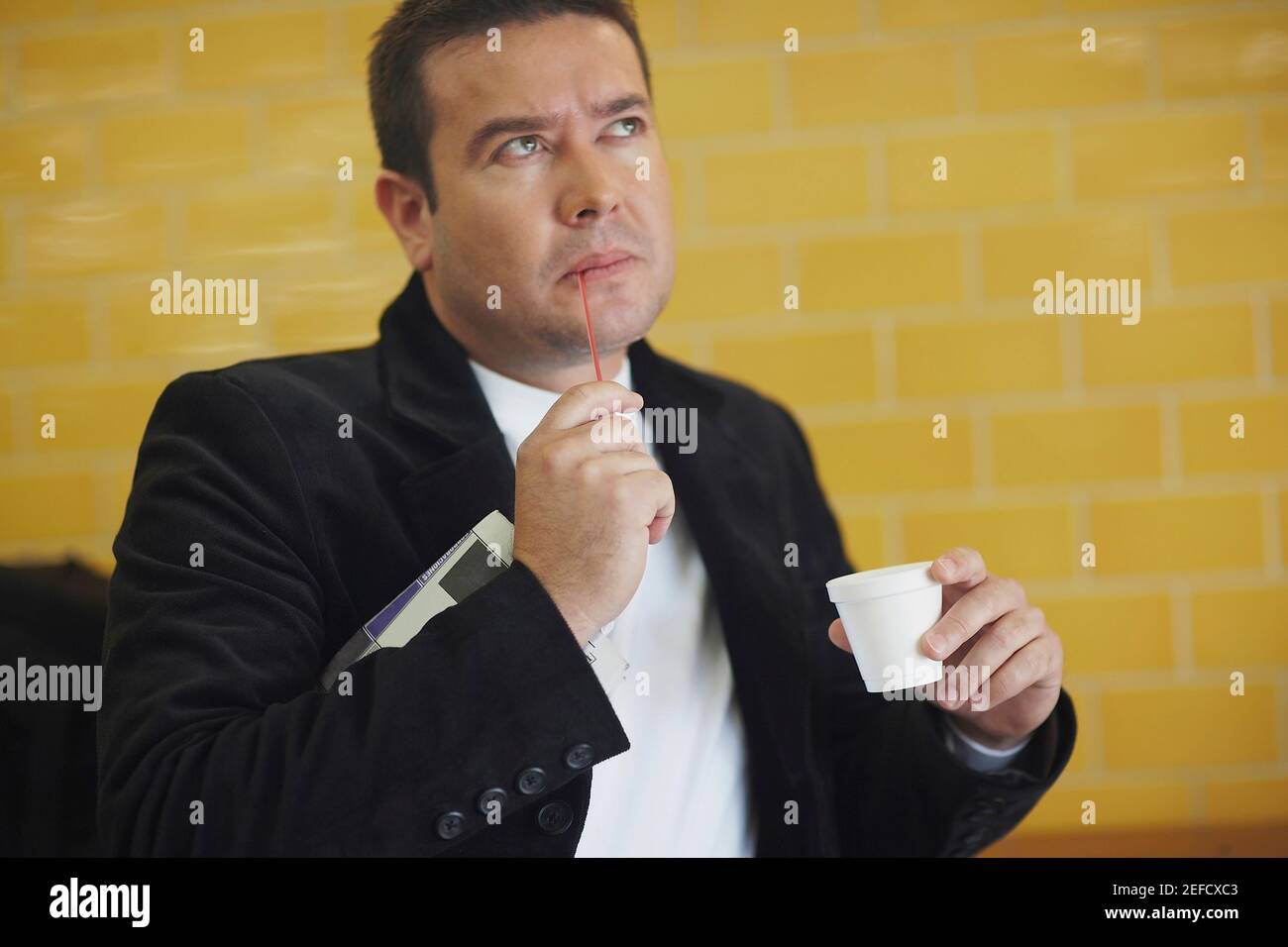 Close up of a mid adult man holding a disposable cup and thinking Stock Photo