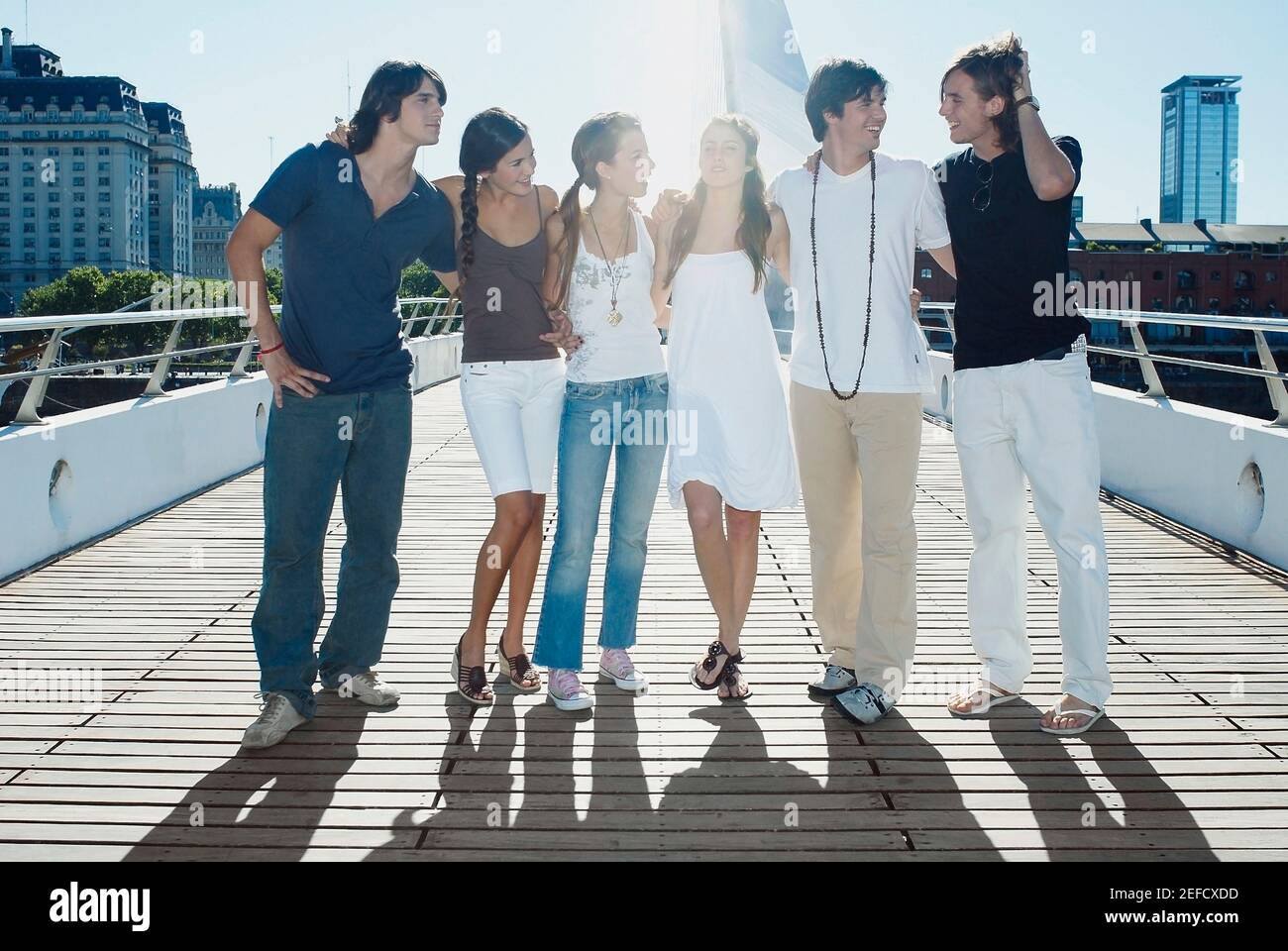 Group of friends with their arms around each other standing on a ...