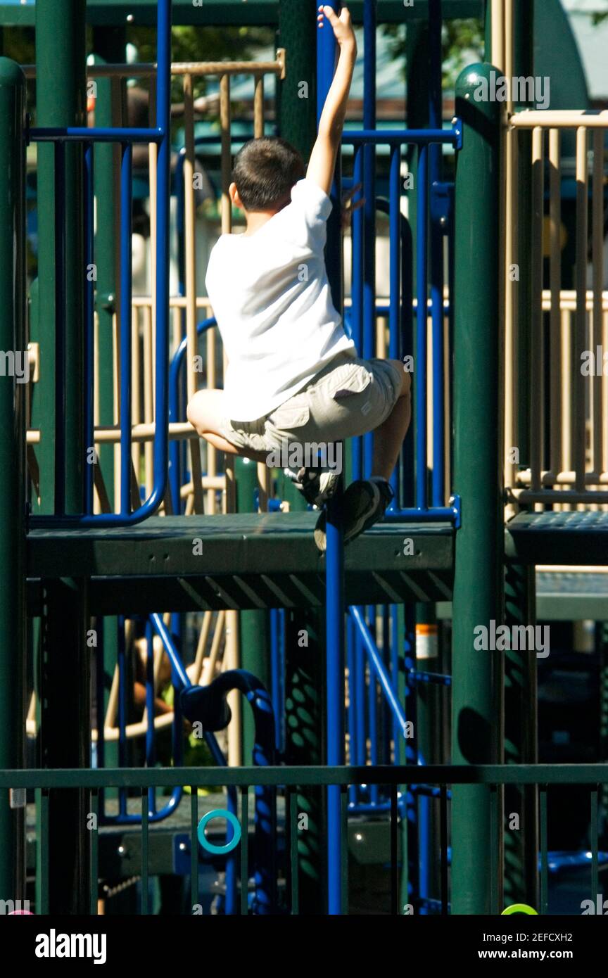 Rear view of a boy clambering on jungle gym Stock Photo