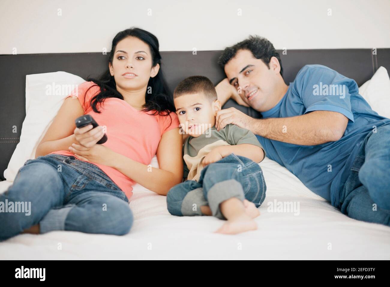 Portrait of a boy lying on the bed with his parents Stock Photo