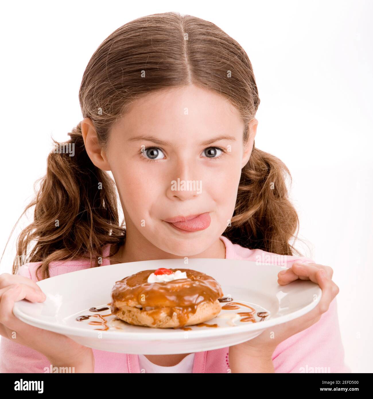 Portrait of a girl holding a donut in a plate licking her lips Stock Photo