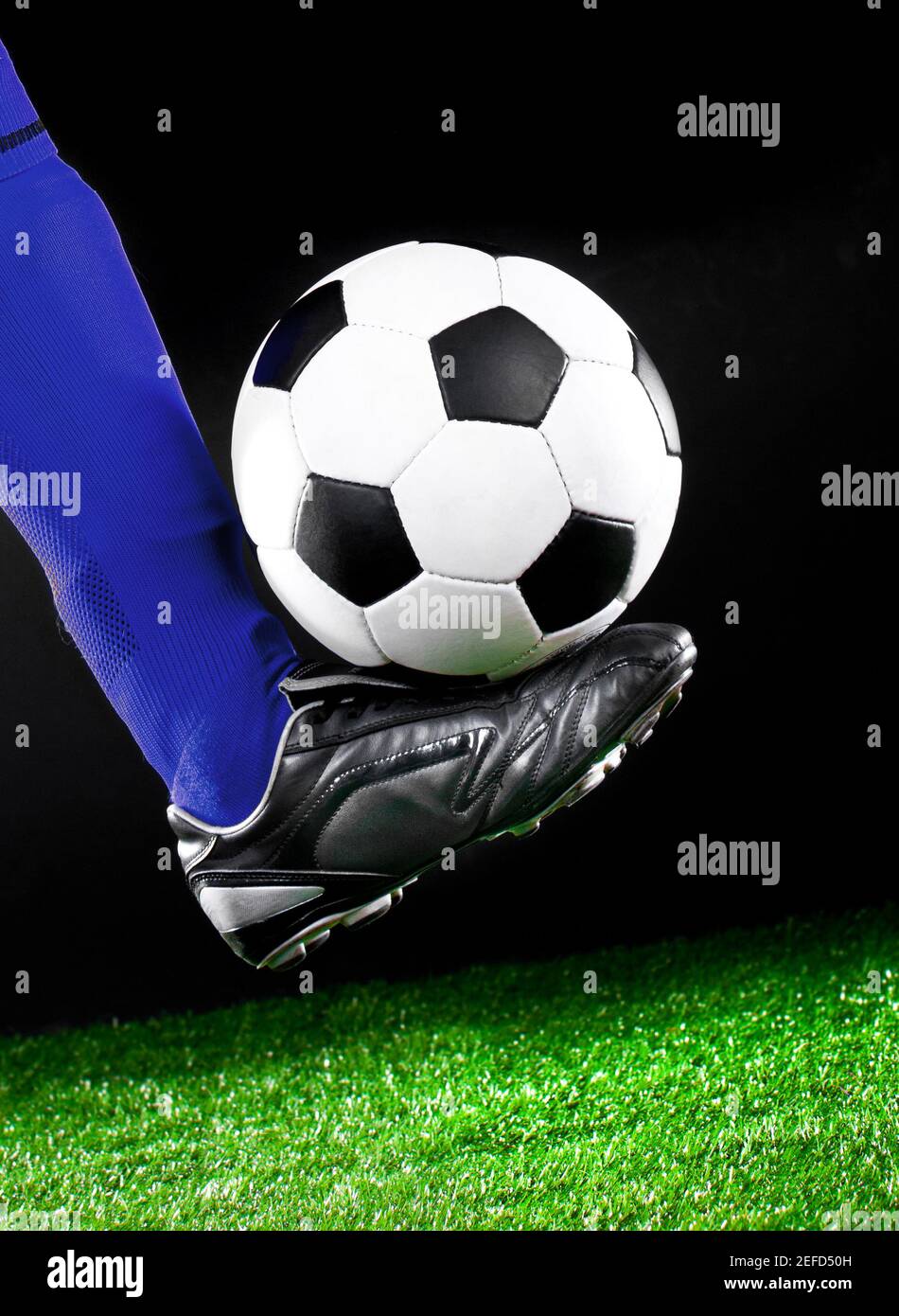 soccer ball and feet on the football field, football player in blue