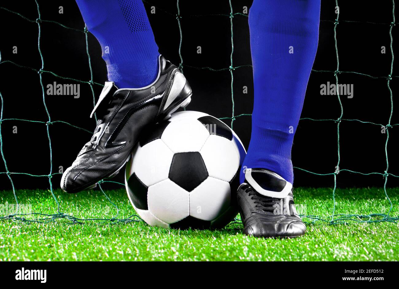 soccer ball and feet on the football field, football player in blue