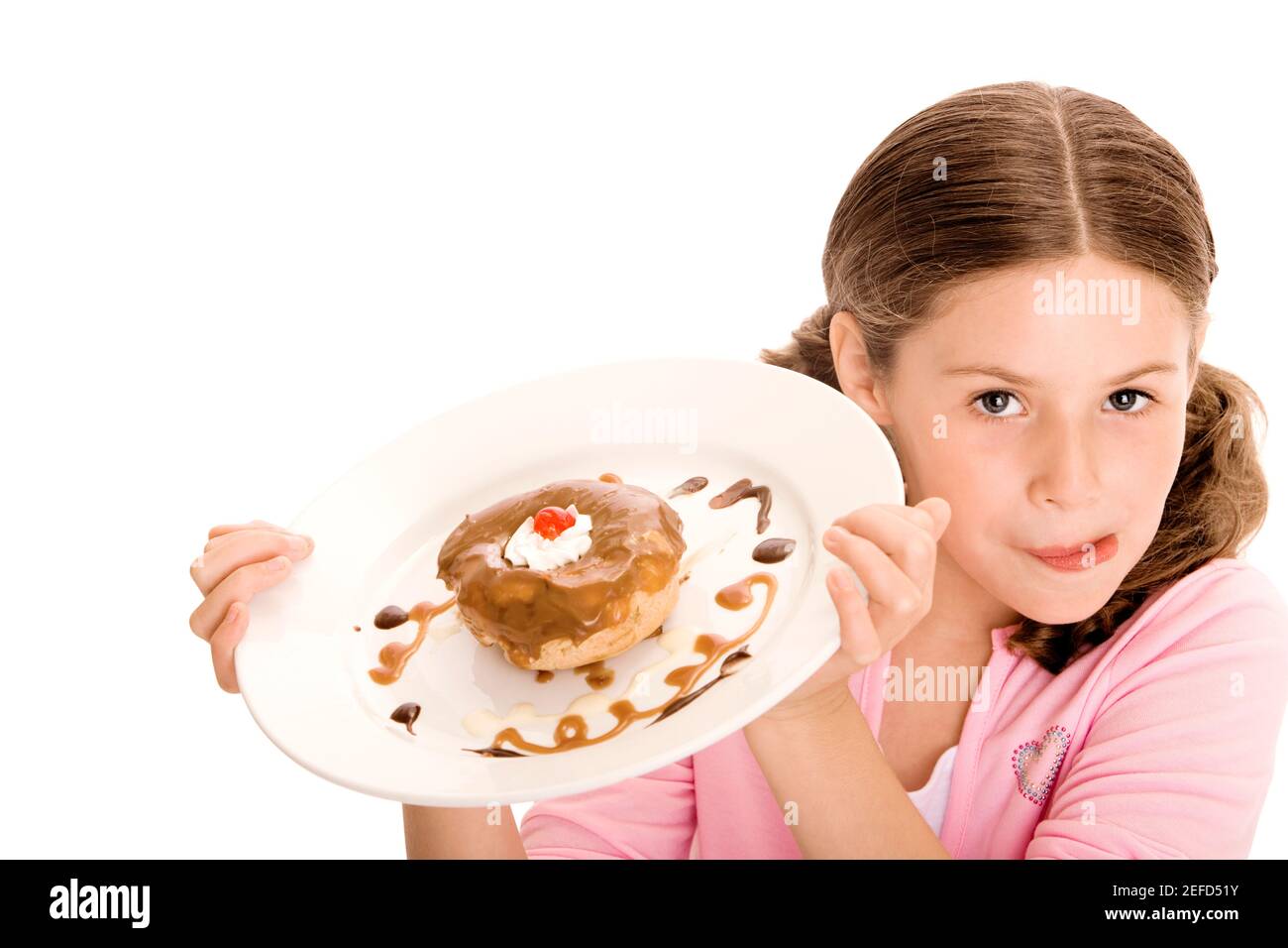 High angle view of a girl holding a donut in a plate licking her lips Stock Photo