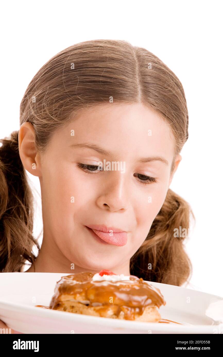 Close-up of a girl holding a donut in a plate licking her lips Stock Photo