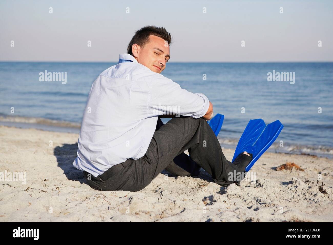 Rear view of a young man sitting on the beach Stock Photo - Alamy