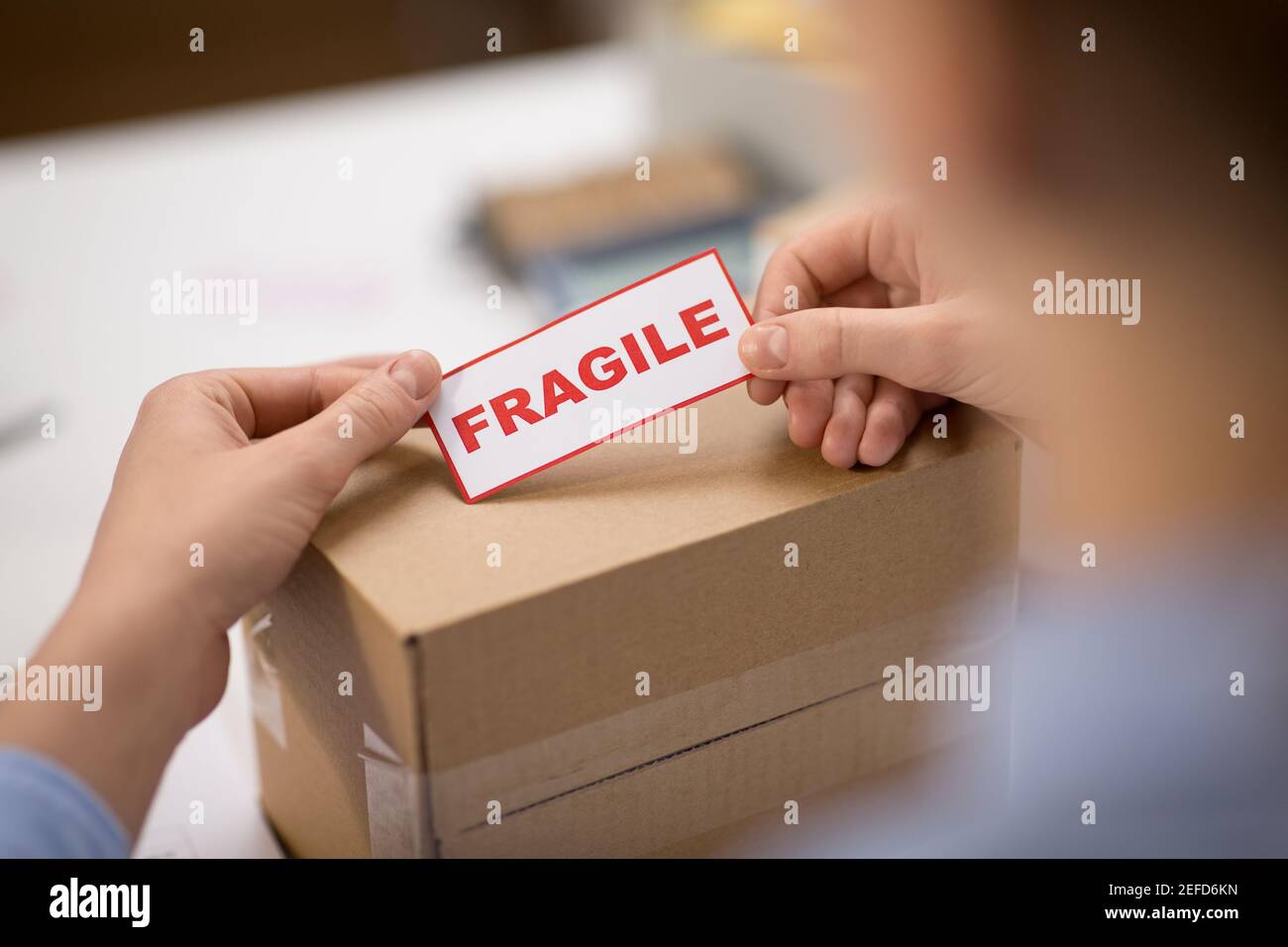 woman sticking fragile mark to parcel box Stock Photo