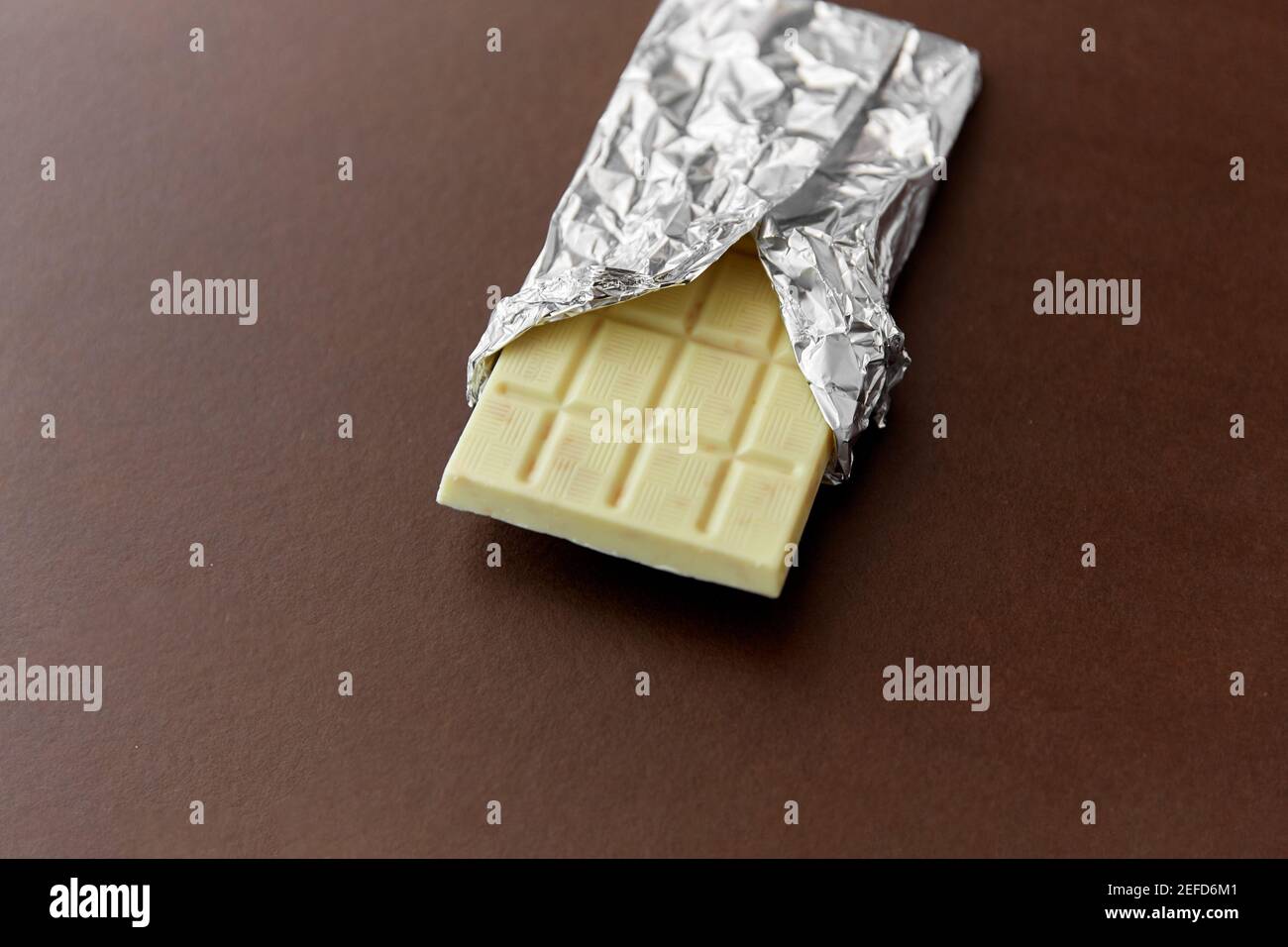 white chocolate bar in foil wrapper on brown Stock Photo Alamy