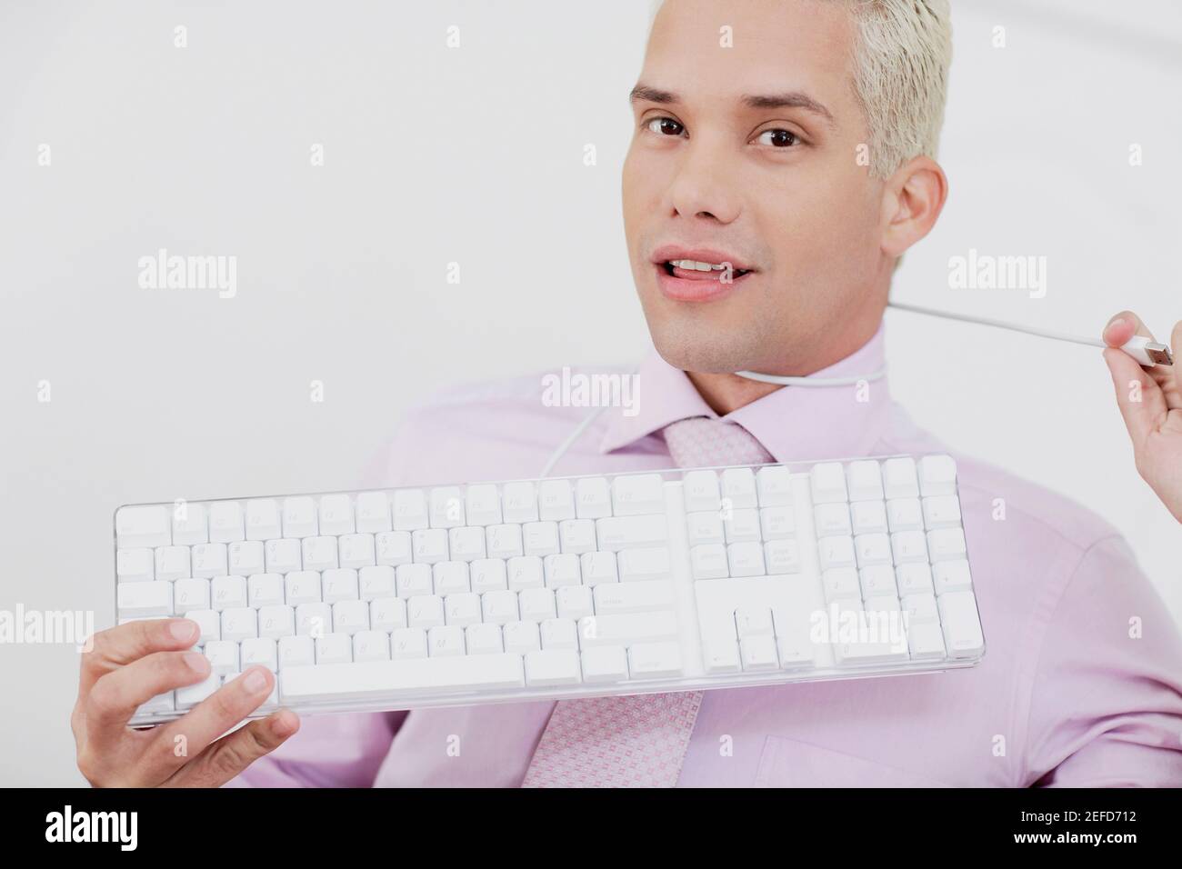 Close up of a young man holding a keyboard with a wire around his neck