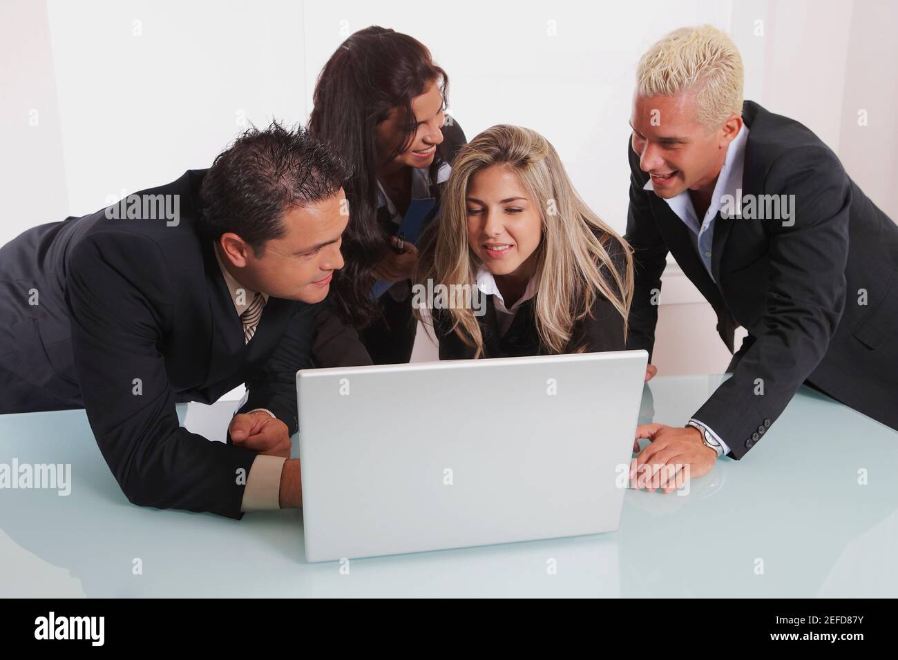 Two businessmen and two businesswomen using a laptop Stock Photo
