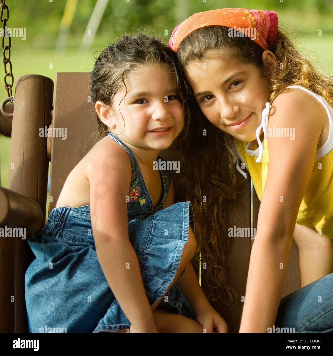 Portrait of two sisters sitting on a swing Stock Photo