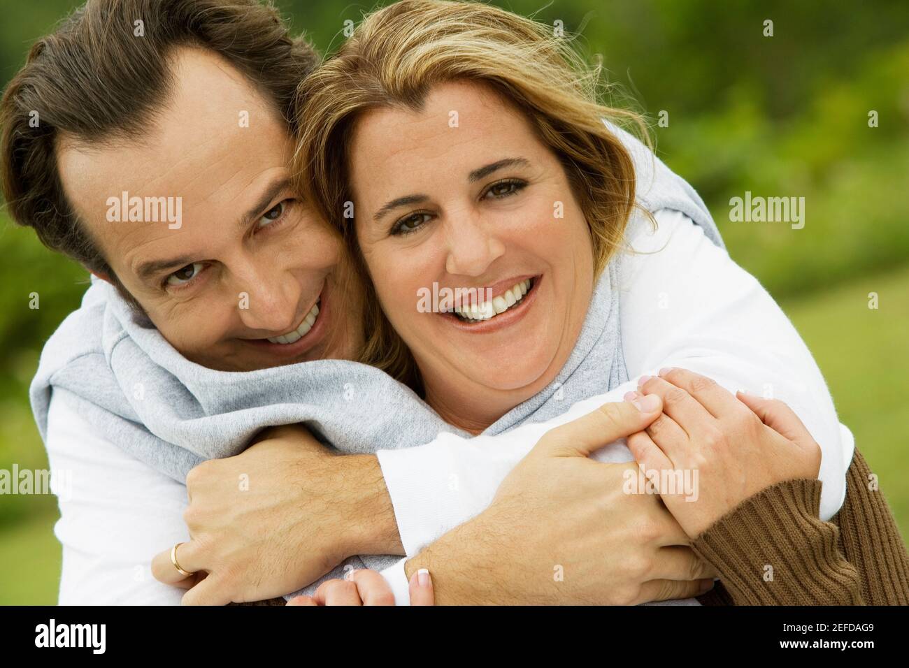 Portrait of a mature man embracing a mid adult woman from behind Stock Photo