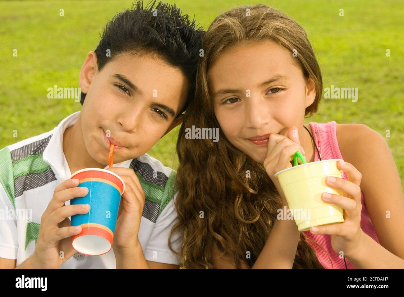 Close-up of a boy and a girl drinking with drinking straws Stock Photo
