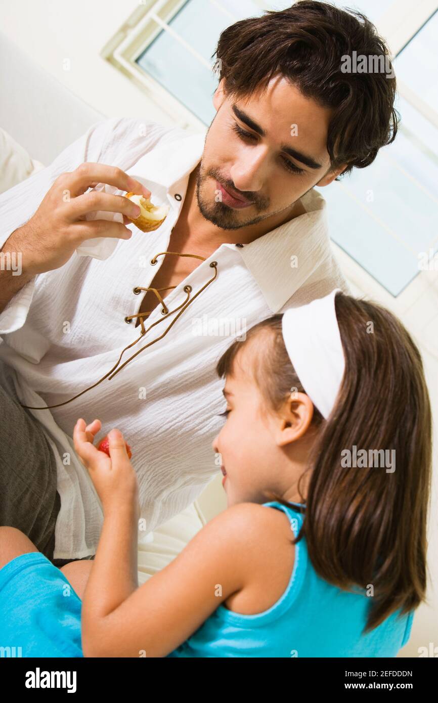 Close-up of a father eating a sandwich with his daughter Stock Photo
