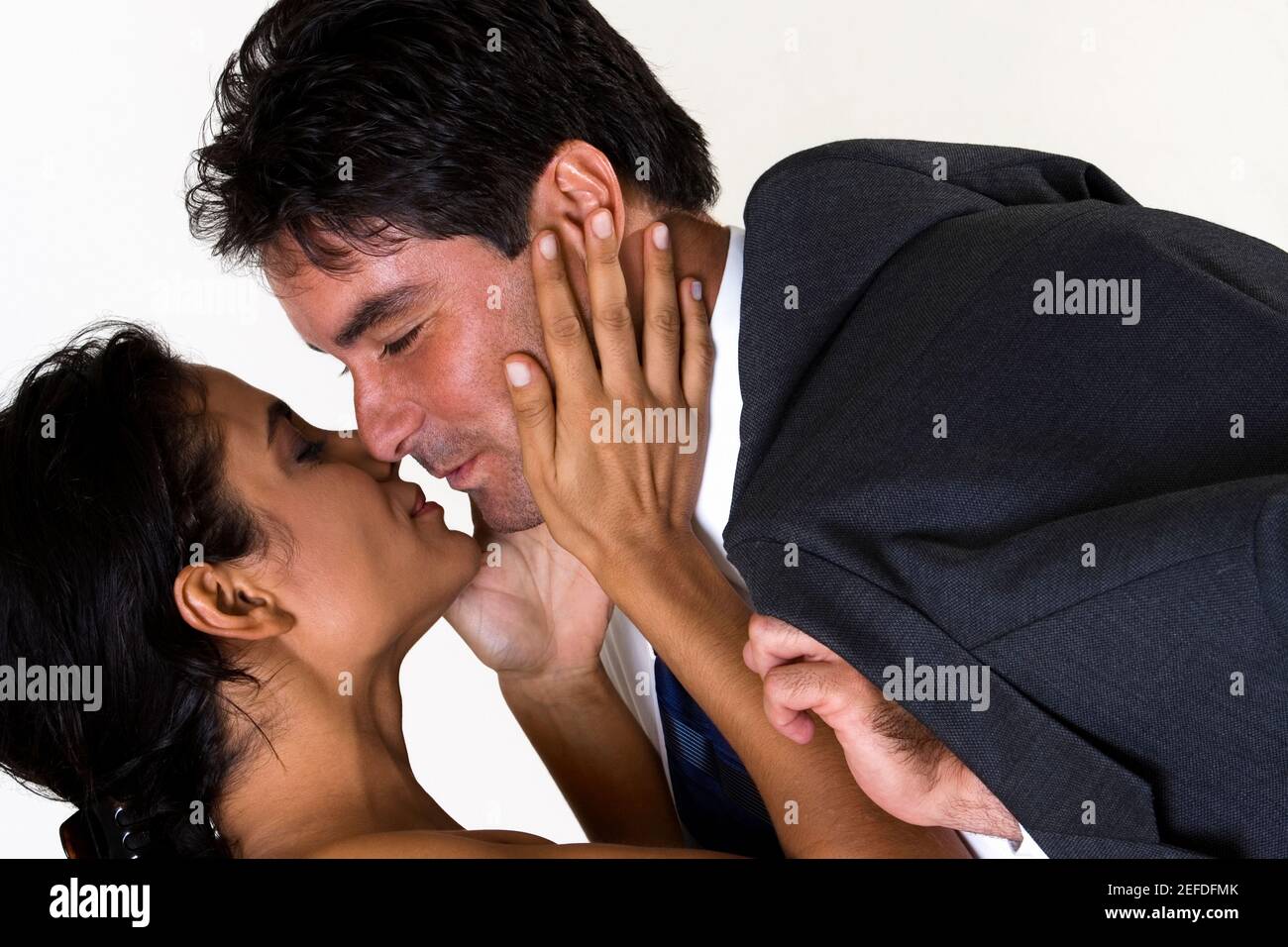 Side profile of a young woman kissing a mid adult man Stock Photo - Alamy