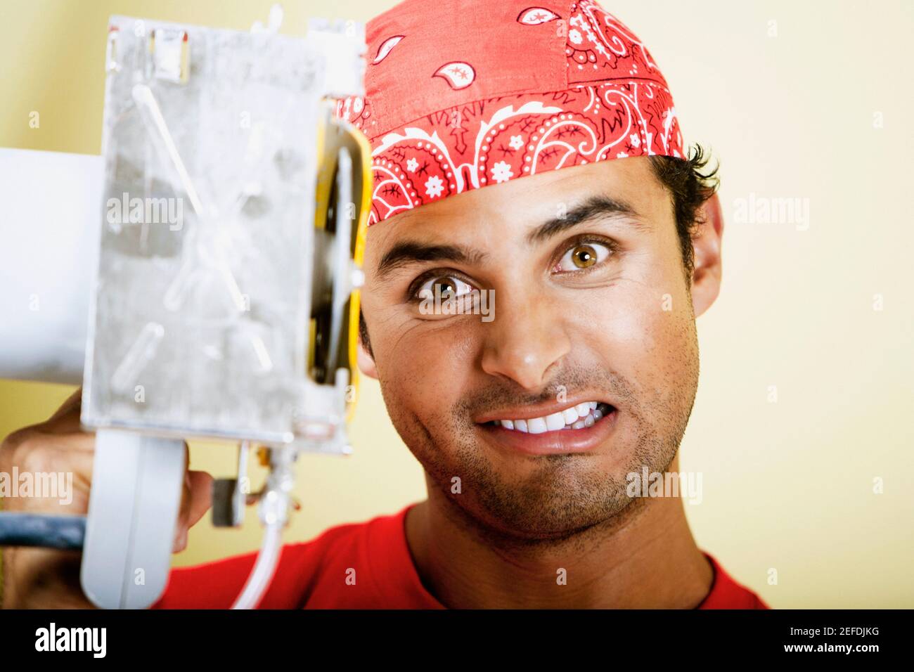 Portrait of a young man holding a circular saw and clenching his teeth Stock Photo