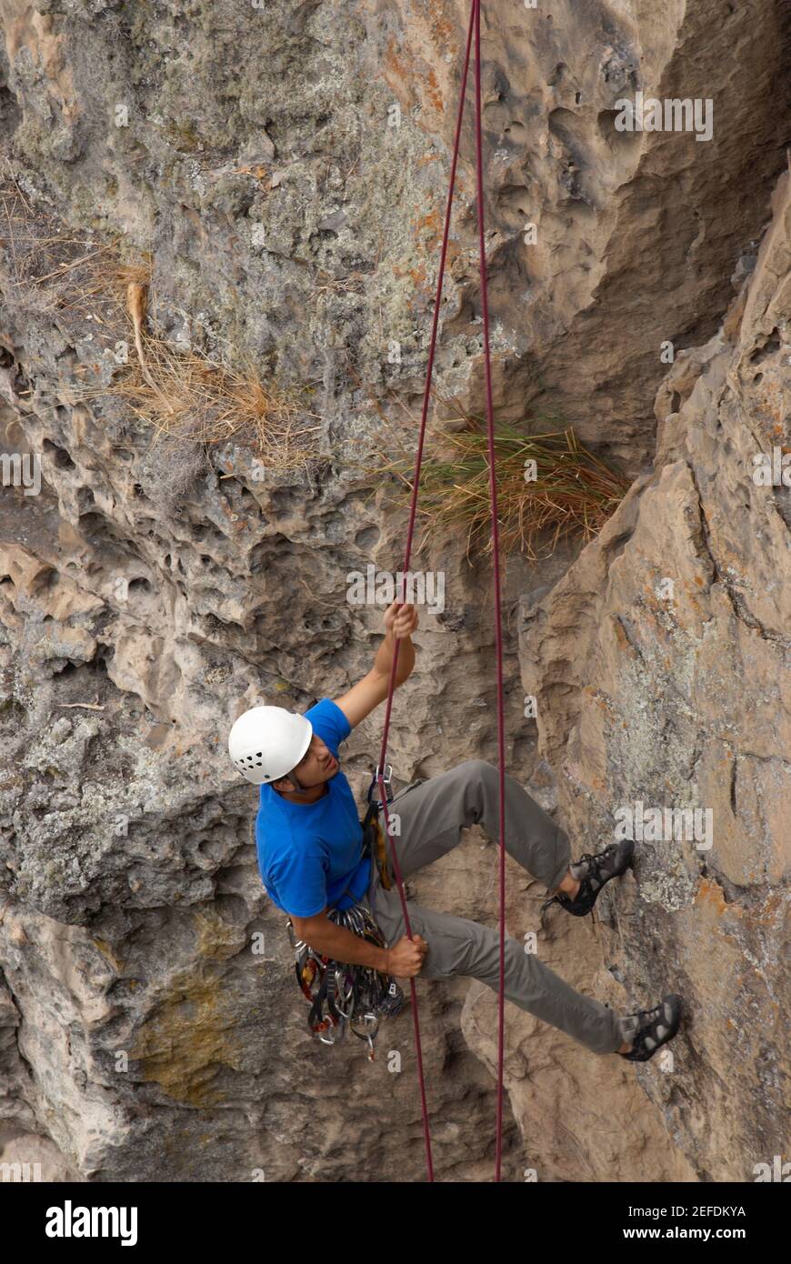 High angle view of a male rock climber scaling a rock face with a rope