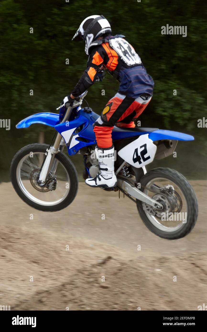 Side profile of a motocross rider performing jump on a motorcycle Stock