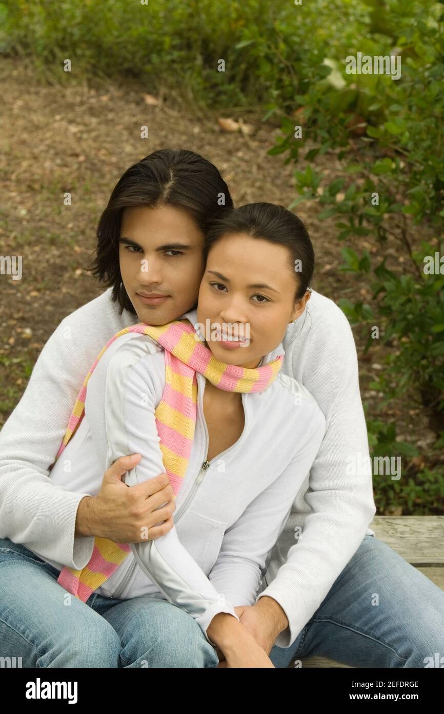 Portrait of a young man embracing a young woman from behind Stock Photo ...
