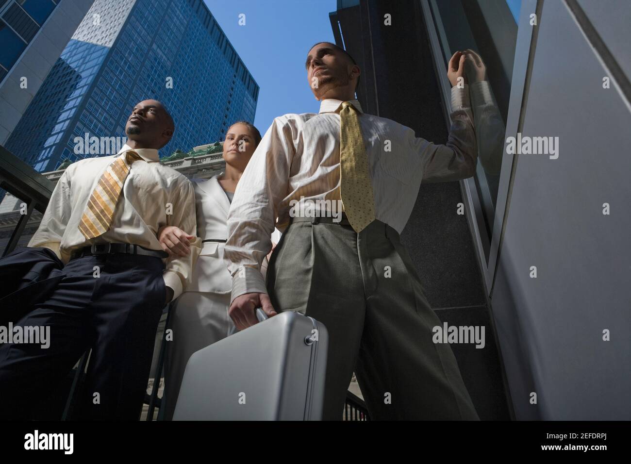 Low angle view of two businessmen and a businesswoman standing together Stock Photo