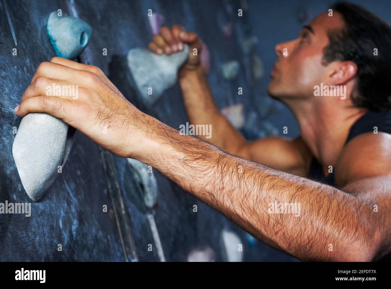Side profile of a mid adult man climbing a wall Stock Photo