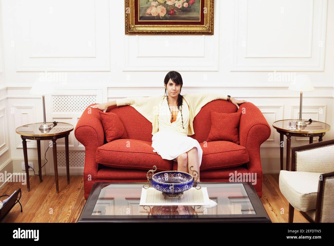 Portrait of a young woman sitting on a couch Stock Photo - Alamy