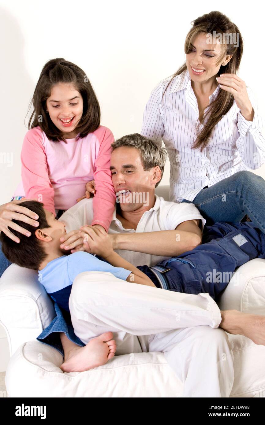 Parents sitting with their son and daughter on an armchair Stock Photo