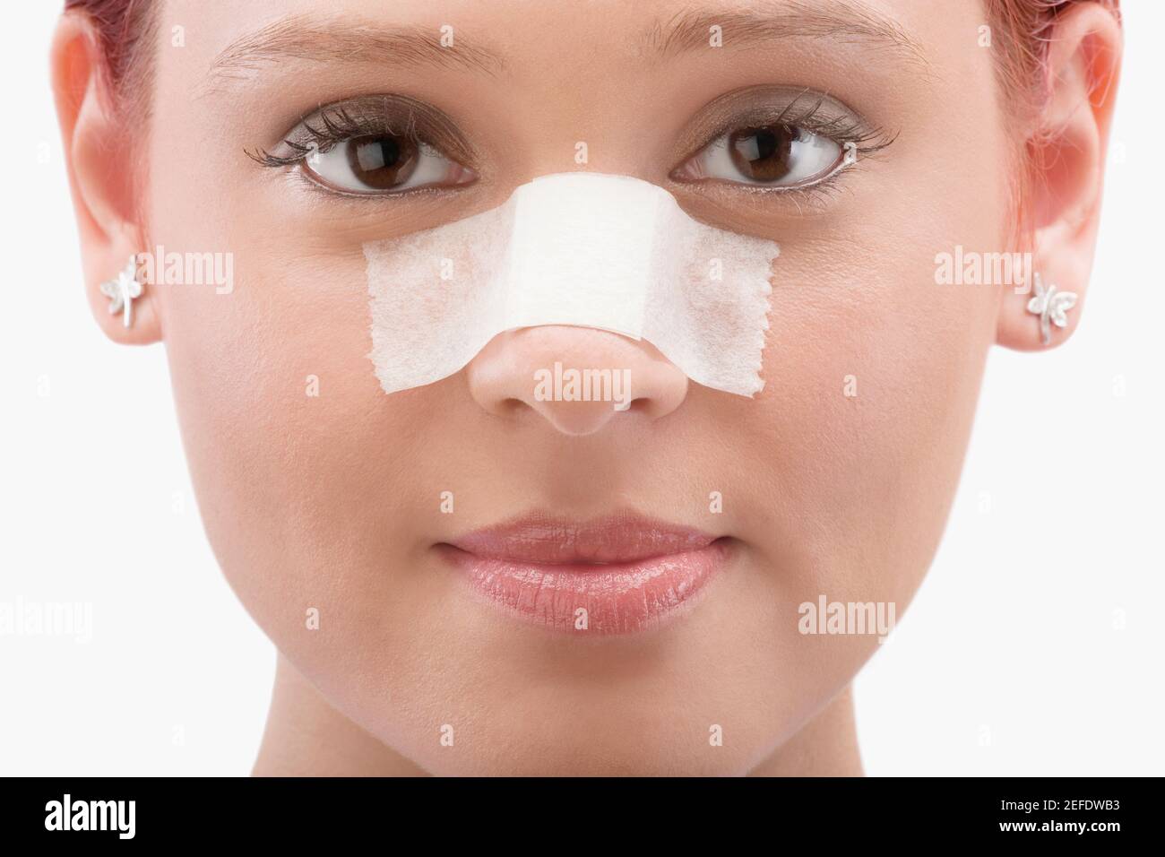 Close up of a female patient with an adhesive bandage on her nose Stock