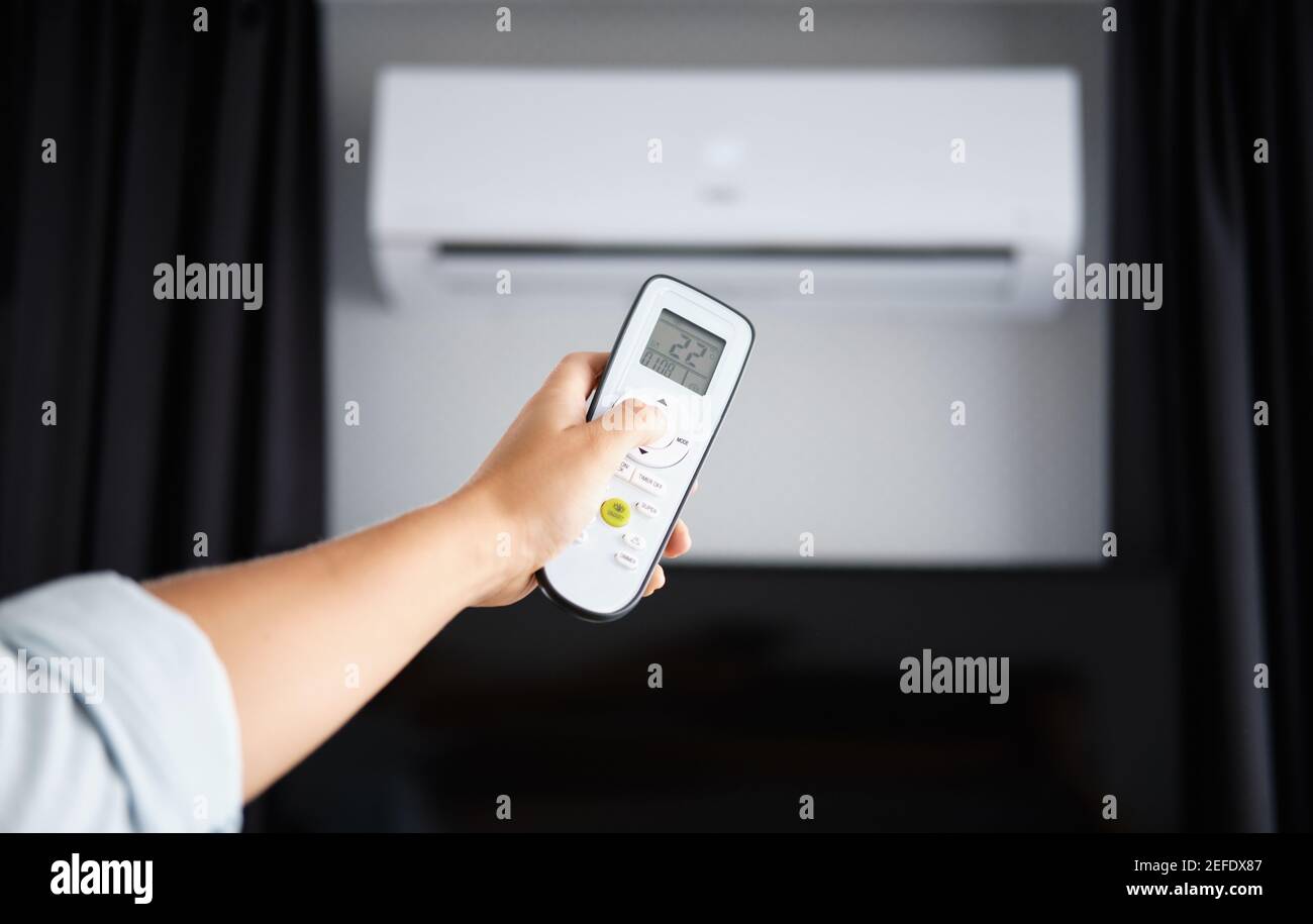 Hand with Remote control on off. Remote Control Directed on the Conditioner Stock Photo