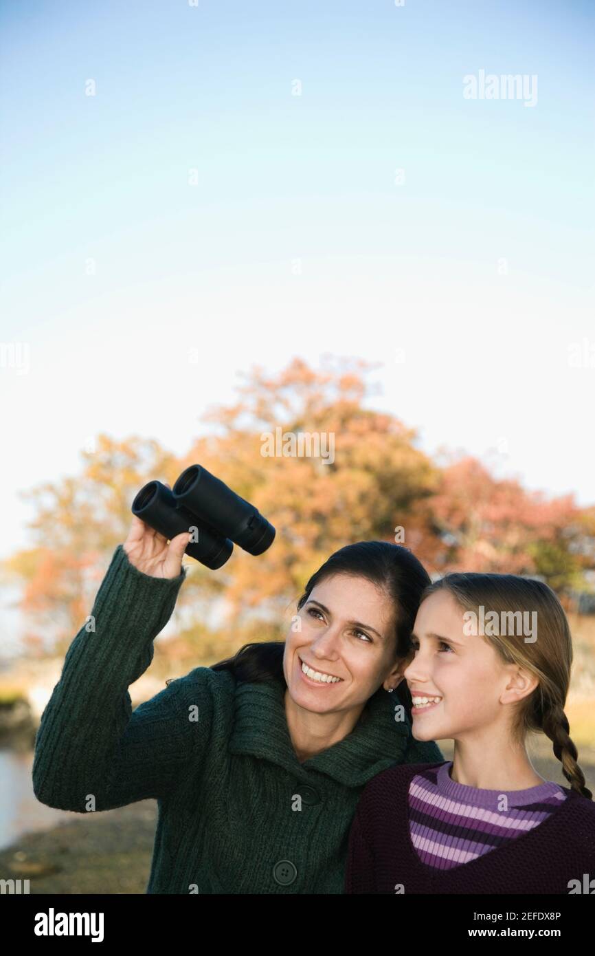 Mid adult woman with her daughter looking through binoculars Stock Photo