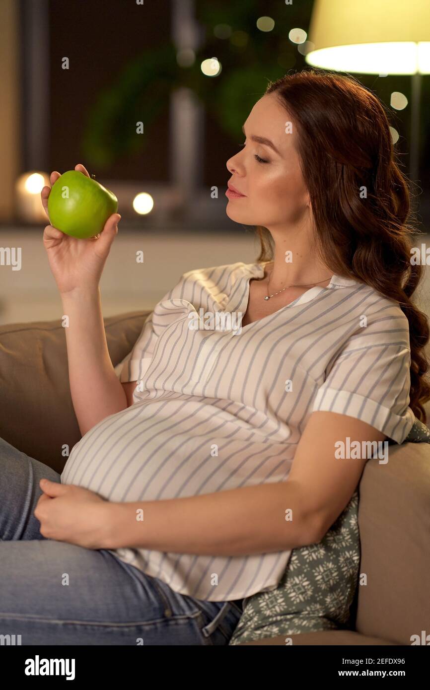 happy pregnant woman with green apple at home Stock Photo
