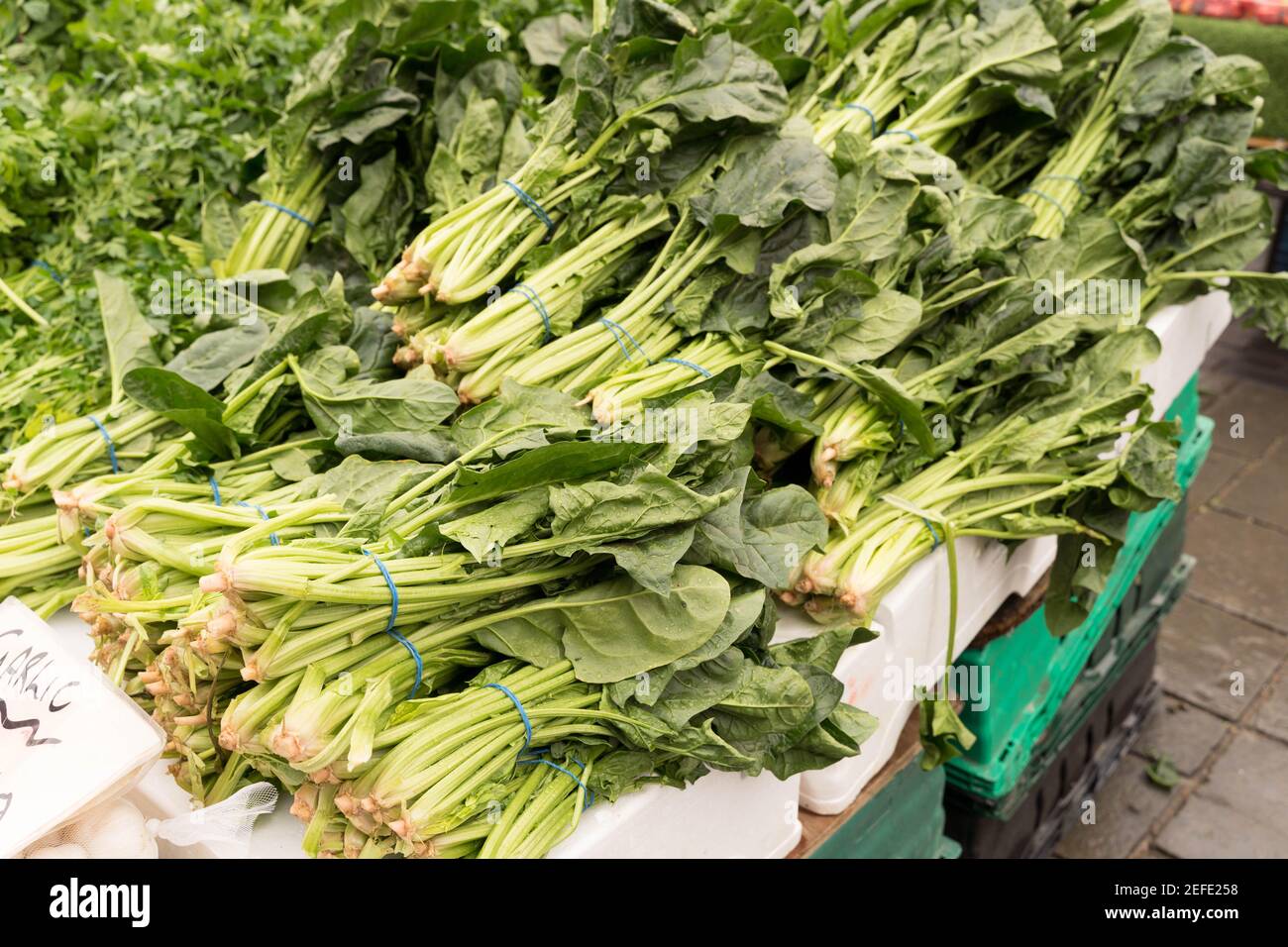 bunches of Spinach on sale in market stall Stock Photo