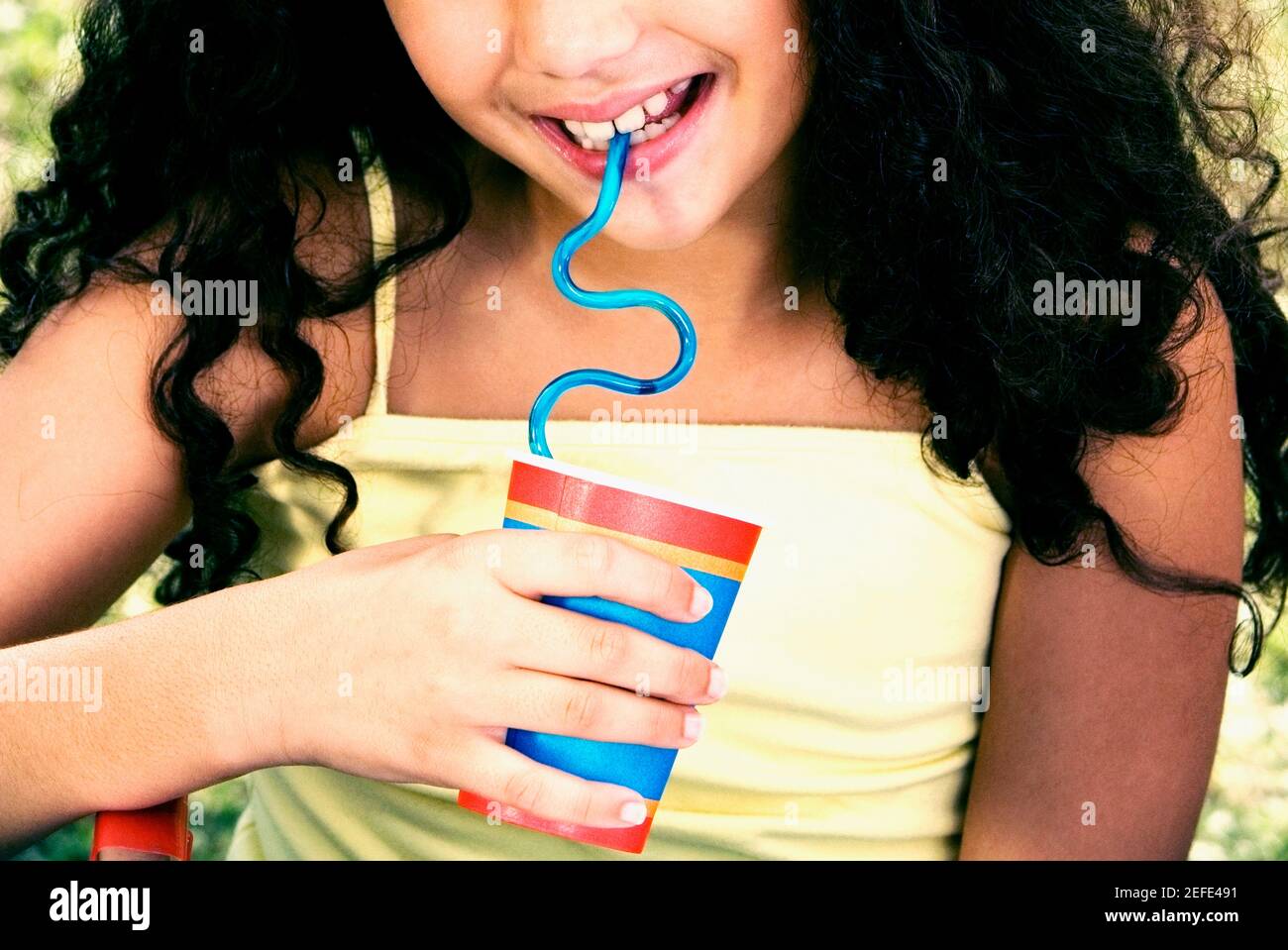 Close-up of a girl holding a disposable cup and drinking with a straw Stock Photo