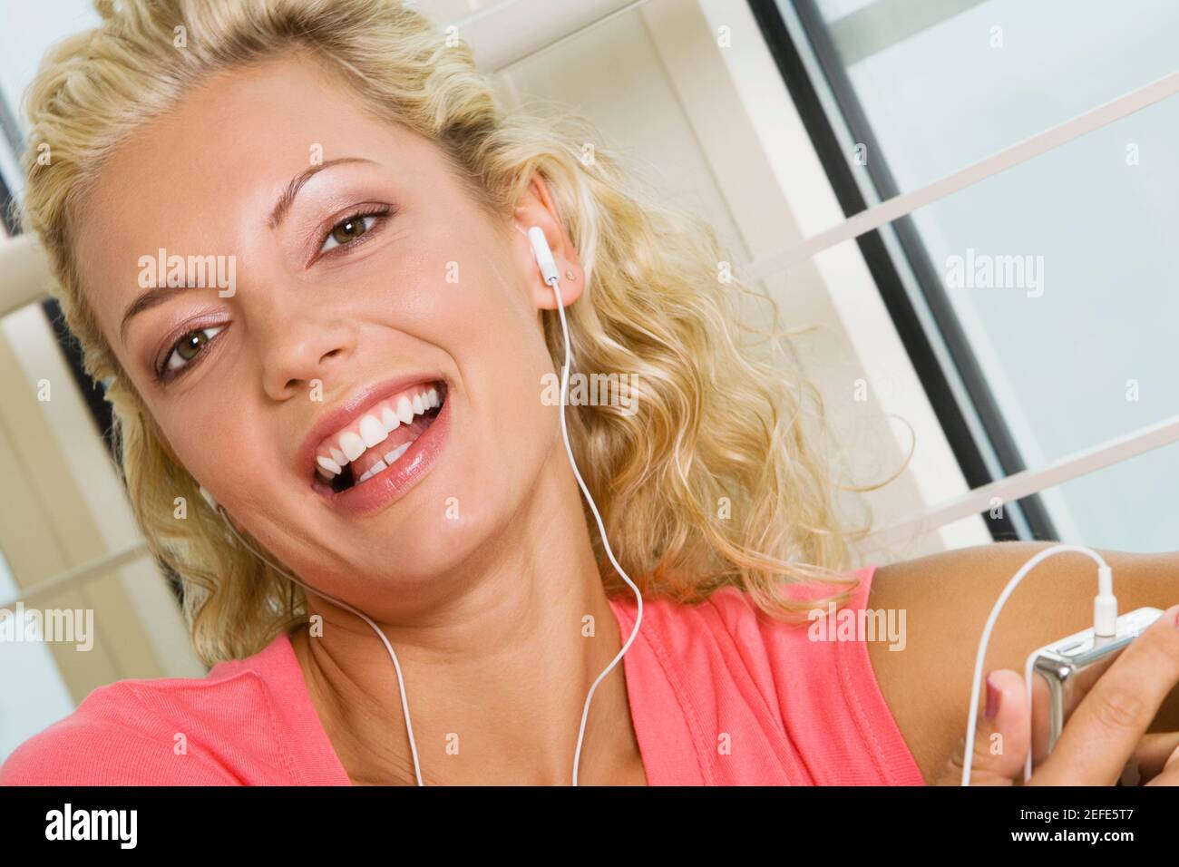 Portrait of a young woman listening to an MP3 player Stock Photo - Alamy