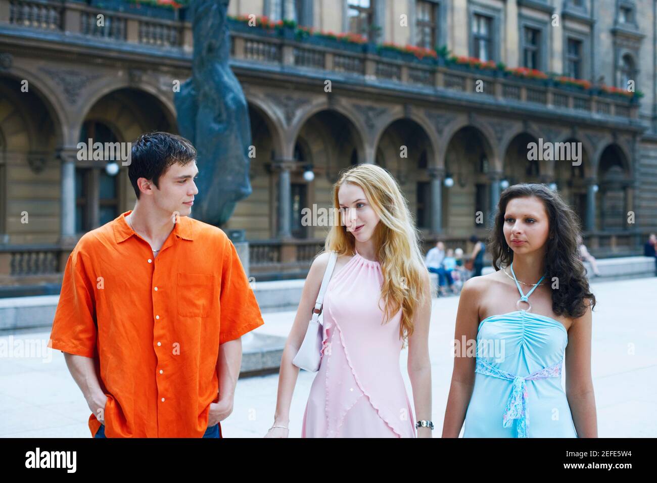 Two young women with a young man walking side by side Stock Photo - Alamy