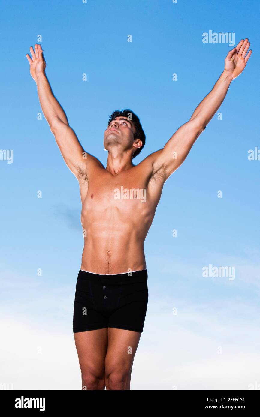 Young man standing with his arms raised Stock Photo - Alamy