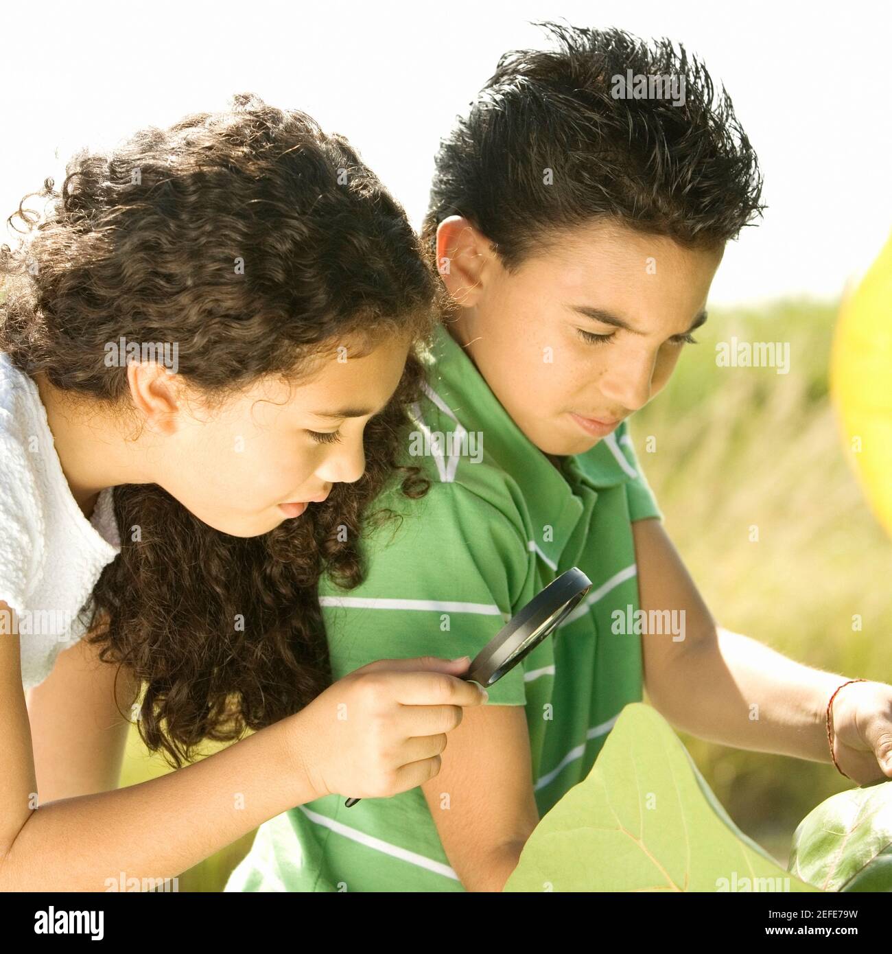 Close-up of a boy and a girl looking through a magnifying glass Stock Photo