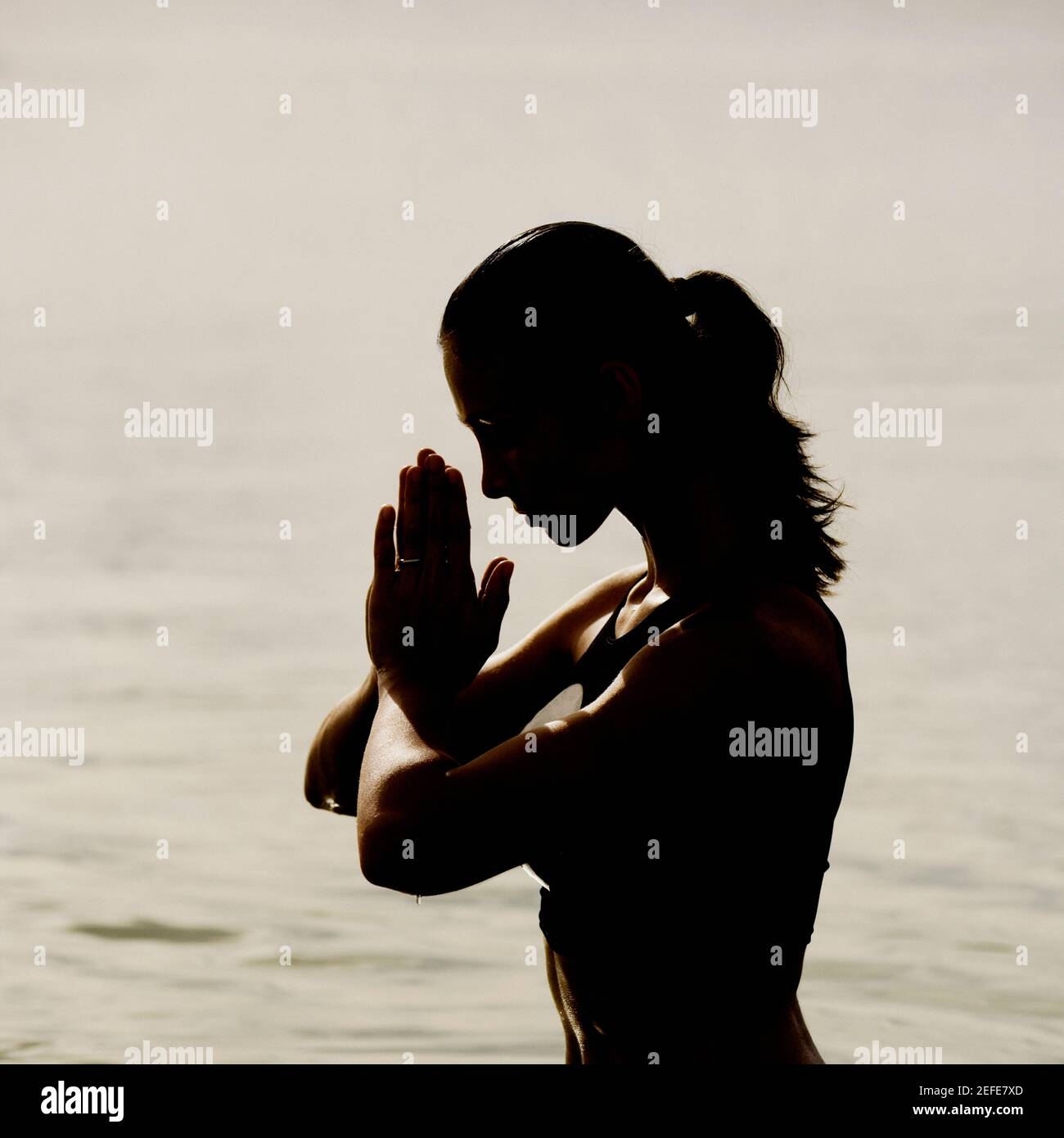 Silhouette of a mid adult woman meditating in water Stock Photo - Alamy