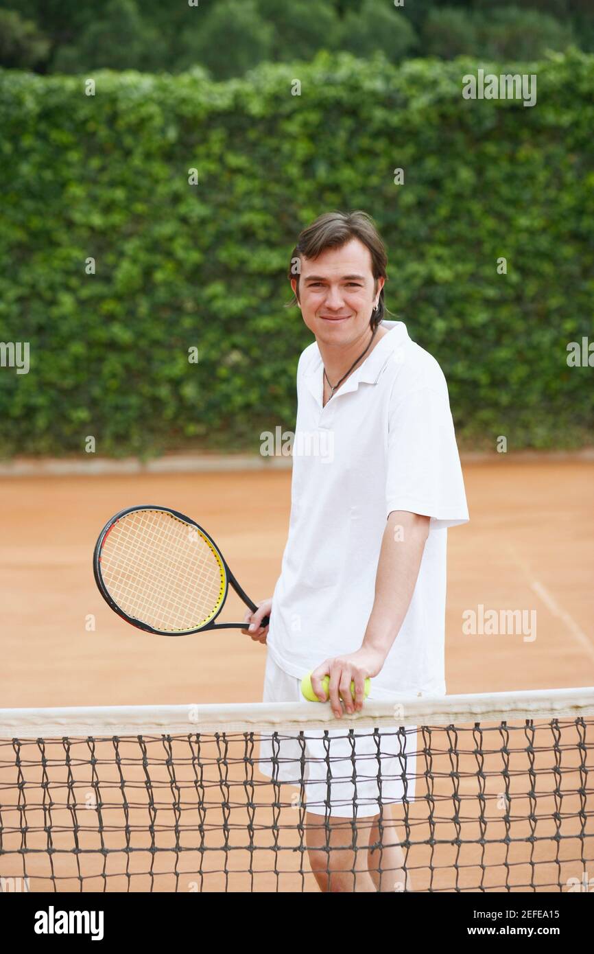 Portrait of a mid adult man holding two tennis balls and a tennis ...