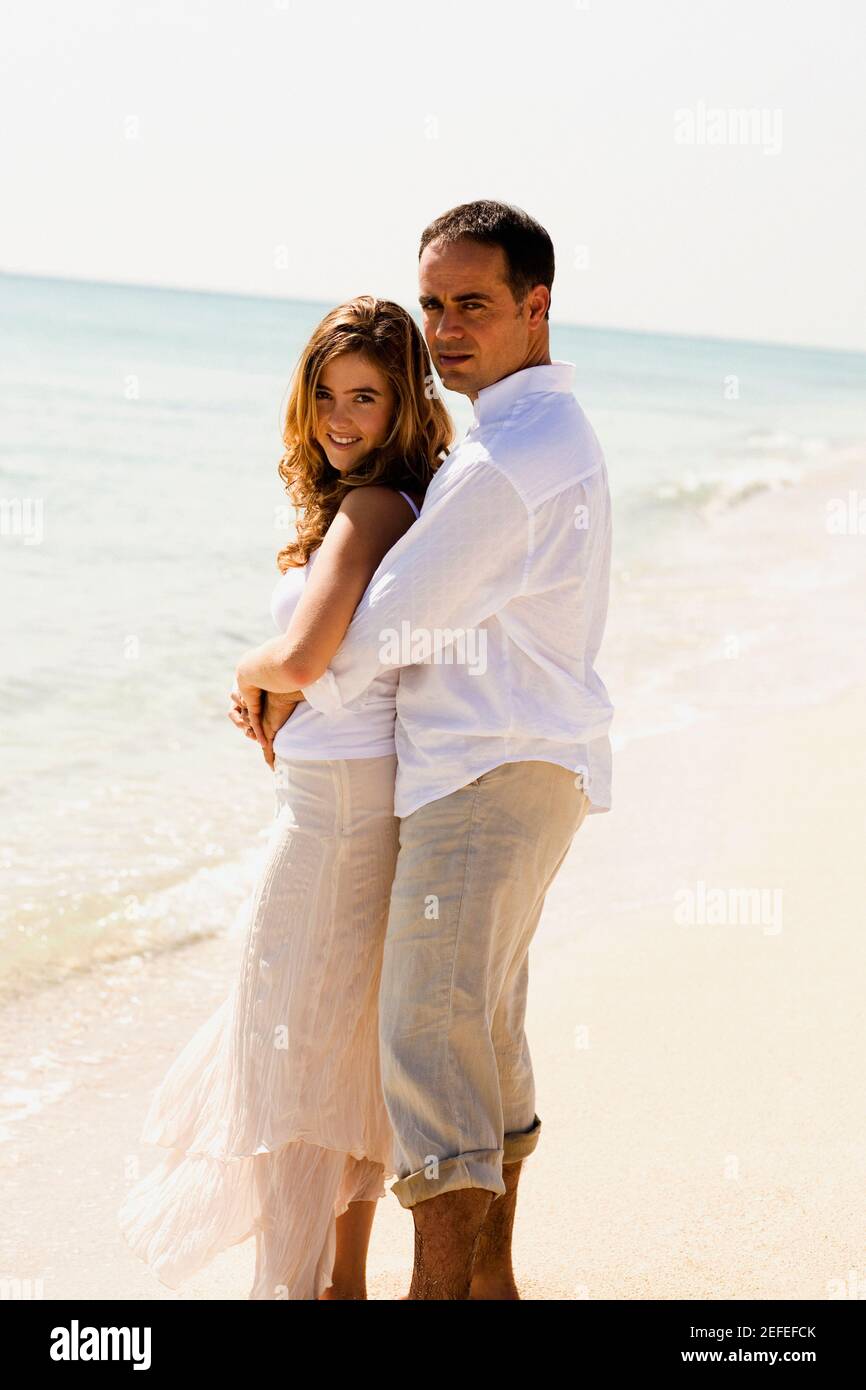 Side profile of a mid adult man embracing a young woman from behind on ...