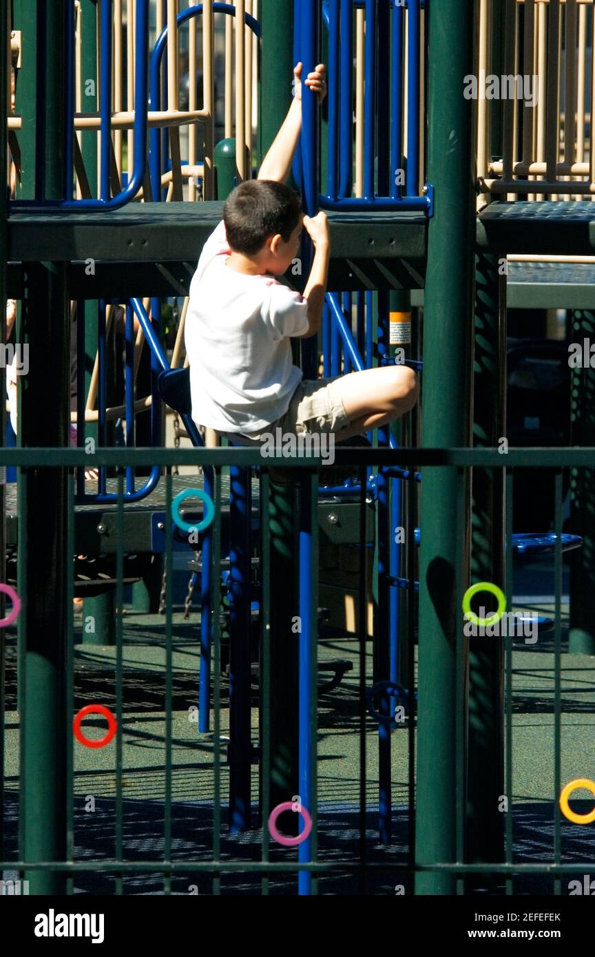 Rear view of a boy clambering on jungle gym Stock Photo