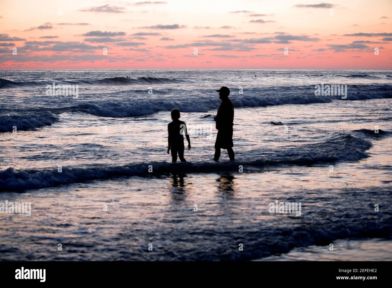 Father and his daughter standing in the water at the beach Stock Photo