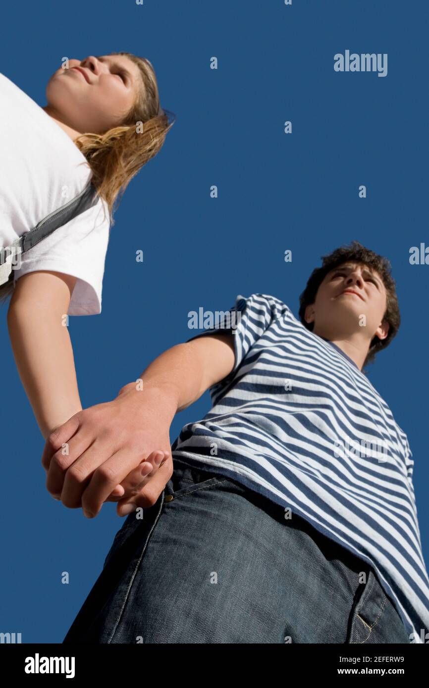 Low angle view of a teenage boy holding hand of his sister Stock Photo