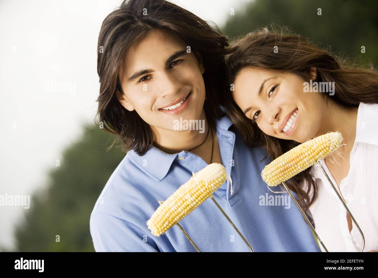 Portrait of a young couple holding corn on the cob Stock Photo - Alamy