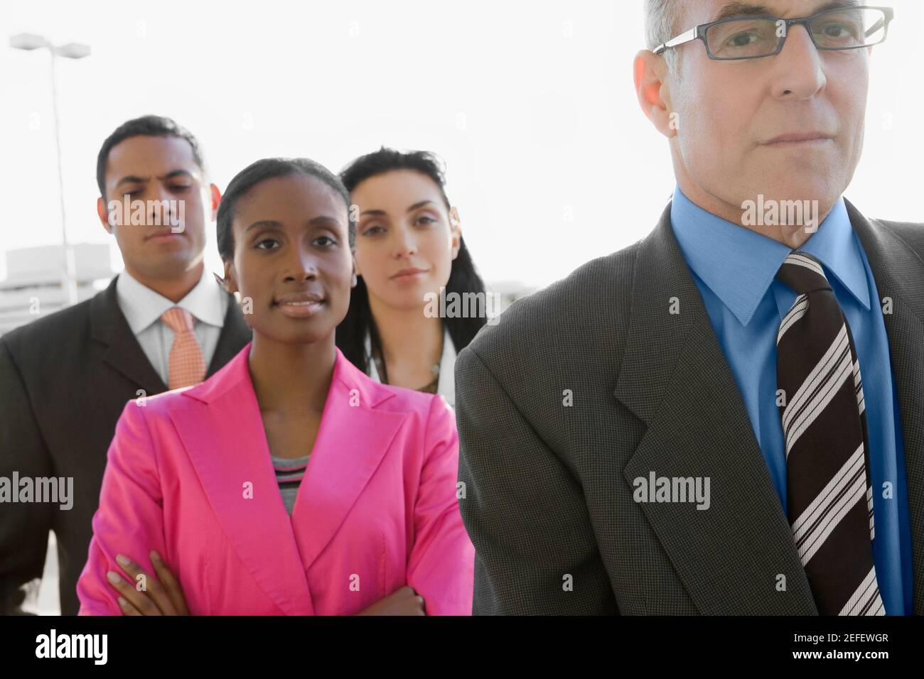 Two businessmen standing at an airport with two businesswomen Stock Photo