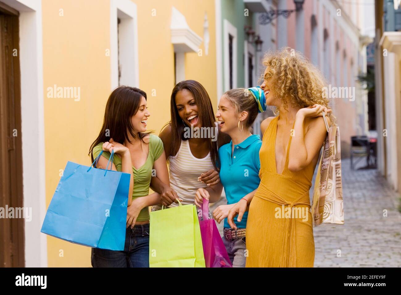 Four teenage girls holding shopping bags and laughing Stock Photo